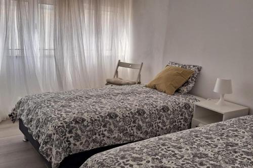 a bedroom with two beds and a chair next to a window at Casa Peixe Nazare in Nazaré