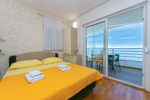 a bedroom with a yellow bed and a balcony at Apartments by the sea Drasnice, Makarska - 6652 in Drasnice