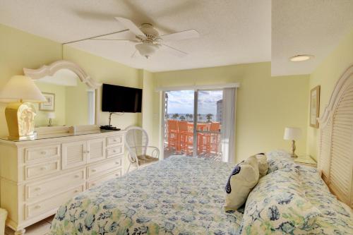 1 dormitorio con 1 cama con tocador y TV en El Matador 144 - Centrally located with a view of the Gulf, en Fort Walton Beach