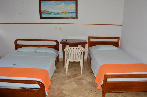 2 Betten in einem Zimmer mit einem Tisch und einem Stuhl in der Unterkunft Hotel Tayrona in Puerto Berrío