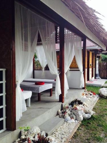 a pavilion with white drapes and a bench and flowers at Liwayway sa Bohol Pamilacan Resort in Baclayon