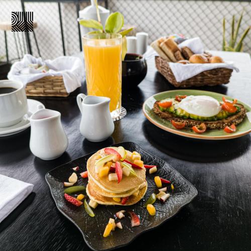 a table with pancakes and a plate of food and a drink at Rua Hoteles Piura in Piura