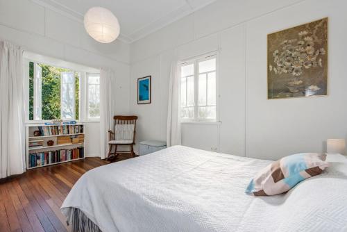 a white bedroom with a bed and a chair at Choongurra in Noosaville