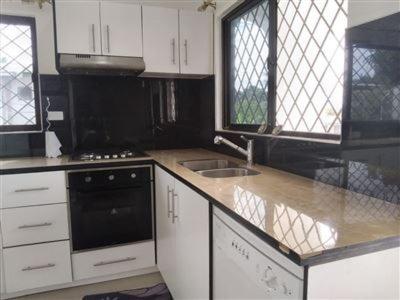 a kitchen with white cabinets and a sink and a stove at Bula Holiday Inn in Nadi