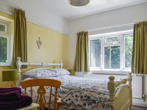 um quarto com uma cama e duas janelas em Ashgrove Cottage em Dudbridge