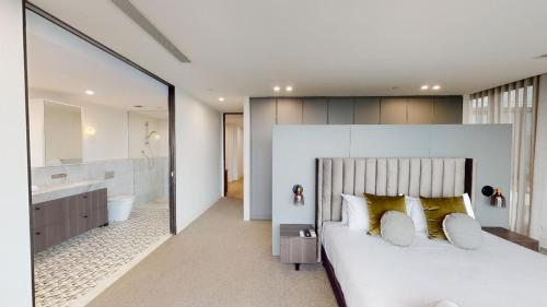 a bedroom with a large white bed and a bathroom at Luxury Penthouse with Astonishing Bay and City Views in Melbourne