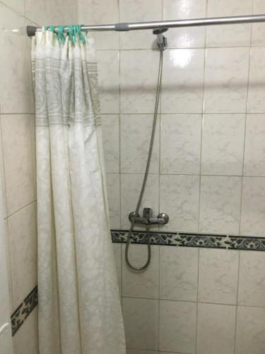 a shower with a white shower curtain in a bathroom at Cami III in Piriápolis