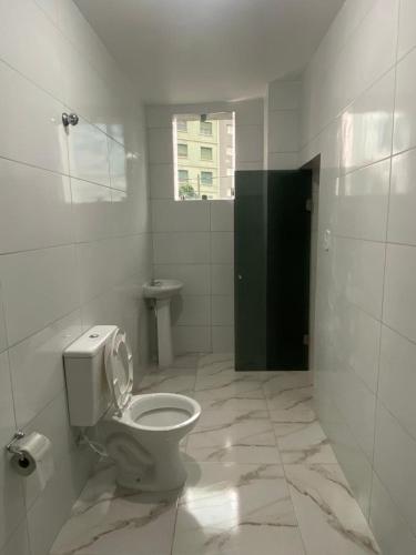 a white bathroom with a toilet and a window at Hotel - Motel Story in São Paulo