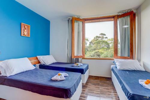 two beds in a room with a window at Pousada Canto de Zul in Itacaré