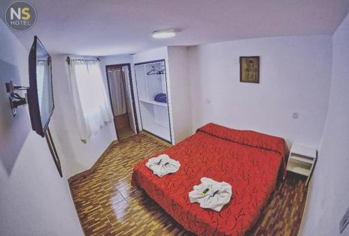 ein Schlafzimmer mit einem roten Bett mit Handtüchern darauf in der Unterkunft Ns Hotel in Termas de Río Hondo