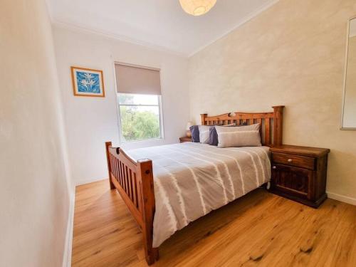 a bedroom with a large bed and a window at Daniu Ocean View Garden House in Merimbula
