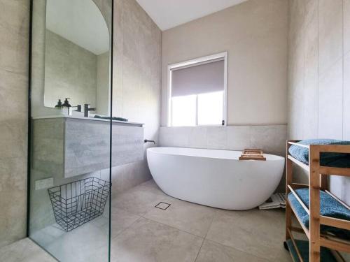 a bathroom with a white tub and a window at Daniu Ocean View Garden House in Merimbula