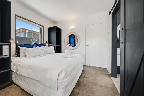 1 dormitorio con 1 cama blanca grande y espejo en 6A Alice Street Jindabyne, en Jindabyne