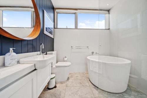 Baño blanco con bañera y lavamanos en 6A Alice Street Jindabyne, en Jindabyne