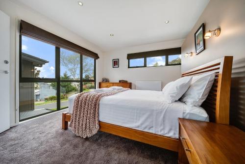 1 dormitorio con cama y ventana grande en Ned Kellys Retreat Sophisticated style with modern convenience and magical outlook, en Jindabyne