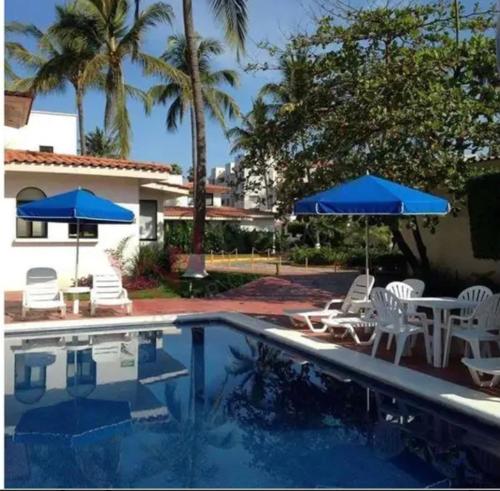 una piscina con sillas y sombrillas junto a una casa en Marina fiesta, en Nuevo Vallarta 