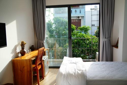 a bedroom with a bed and a desk and a large window at Laholm Hotel - Apartment in Nha Trang