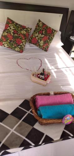 a white bed with a basket of towels and a purse at Cabaña en el Campo in La Vega