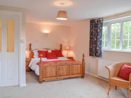 a bedroom with a wooden bed with red pillows at Ripple Farm Cottage in Great Mongeham