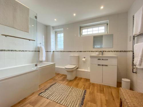 a bathroom with a toilet and a tub and a sink at Ripple Farm Cottage in Great Mongeham