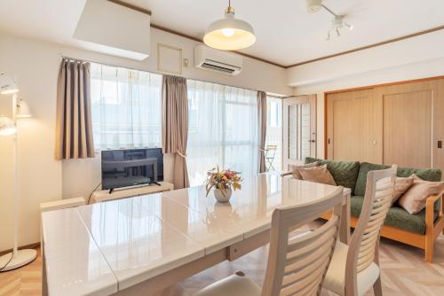 eine Küche und ein Wohnzimmer mit einem Tisch und einem Sofa in der Unterkunft Universal Bay Condominium in Osaka