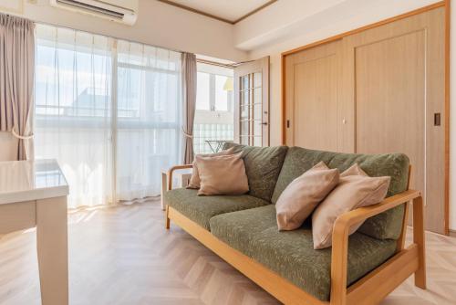 a living room with a green couch with pillows at Universal Bay Condominium in Osaka