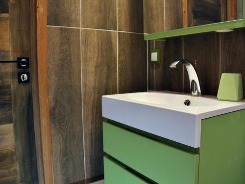 La salle de bains est pourvue d'un lavabo blanc et de placards verts. dans l'établissement Chalet duplex avec poêle à bois, parking et WiFi - FR-1-343-166, à Chamonix-Mont-Blanc