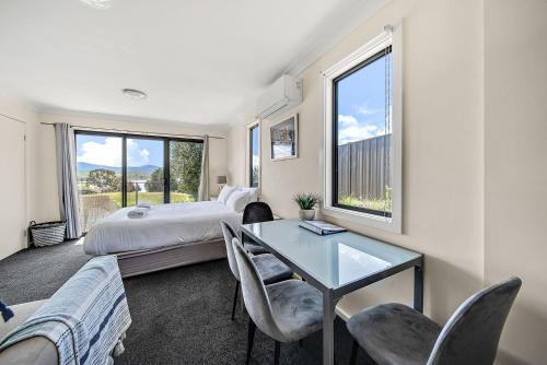 a bedroom with a bed and a table and chairs at Poley Cow Studio Lakeviews in Jindabyne