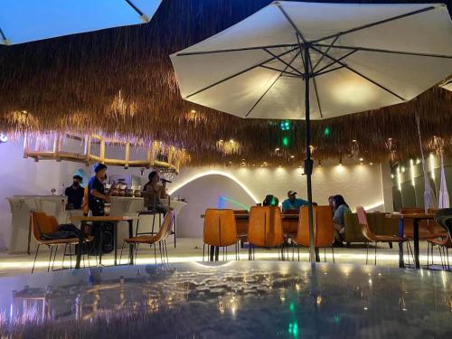 ein Restaurant mit Tischen, Stühlen und einem Sonnenschirm in der Unterkunft Bassa nova villa in Panglao