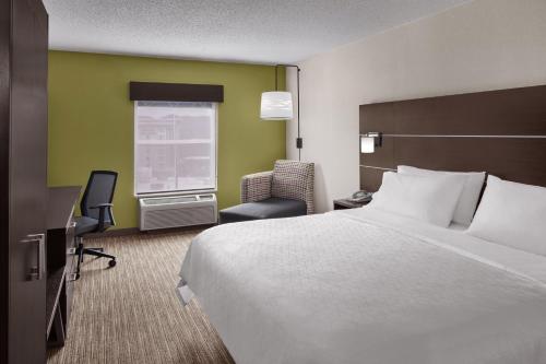 a hotel room with a bed and a chair at Holiday Inn Express & Suites Asheville SW - Outlet Ctr Area, an IHG Hotel in Asheville