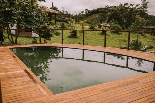 a swimming pool with a wooden deck next to a house at Sítio do Filipe na Cachoeira do Tabuleiro in Conceição do Mato Dentro