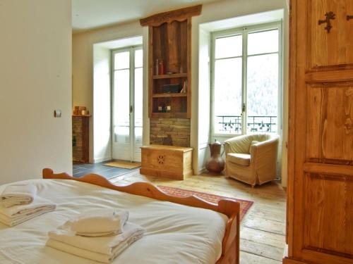 1 dormitorio con 1 cama, 1 silla y ventanas en Appartement Chamonix-Mont-Blanc, 2 pièces, 4 personnes - FR-1-343-209, en Chamonix-Mont-Blanc