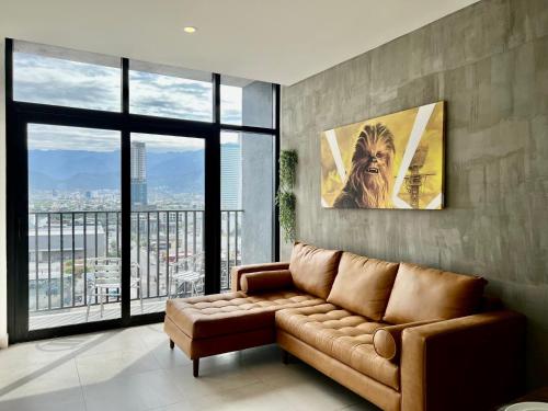 ein Wohnzimmer mit einem braunen Sofa und großen Fenstern in der Unterkunft Industrial stylish 3-br. apartment & city views in front of Parque Fundidora & Arena Mty in Monterrey