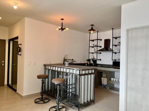 a kitchen with a bar with stools at Industrial stylish 3-br. apartment & city views in front of Parque Fundidora & Arena Mty in Monterrey