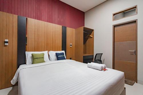 a bedroom with a large white bed and a door at Urbanview Elephant Eleven Residence Bandung in Bandung