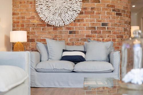 a couch in front of a brick wall at Coastal Retreat 10 Champagne Court in Tuncurry