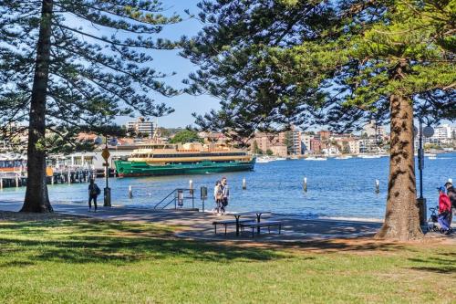 a boat on the water with people walking on a park at Best location in Manly Harbour view in Sydney