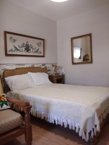 a bedroom with a bed and a mirror and a chair at Ξενώνας Το Πέτρινο 2 in Keramídhion