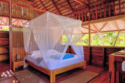 a bedroom with a canopy bed in a hut at Loedi Bungalows Rote in Nembrala