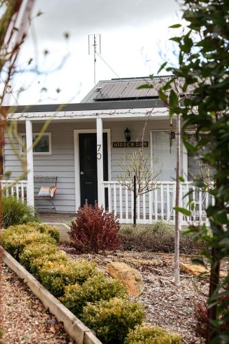 a white house with a bench on the front porch at Hidden Gem ~ Luxury Cottage near Lake Daylesford in Daylesford