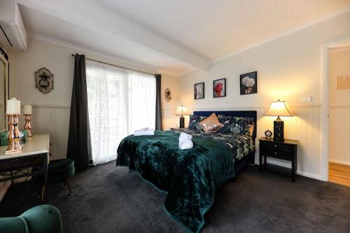a bedroom with a green bed and a window at Hidden Gem ~ Luxury Cottage near Lake Daylesford in Daylesford