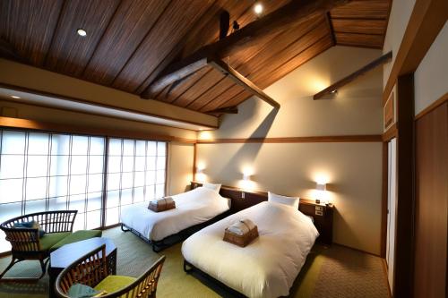 a bedroom with two beds and a table and chairs at Yasaka Yutone Kyokoyado in Kyoto