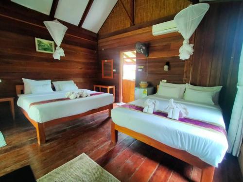 two beds in a room with wooden walls and wooden floors at Phoxay Ngam Resort in Vang Vieng