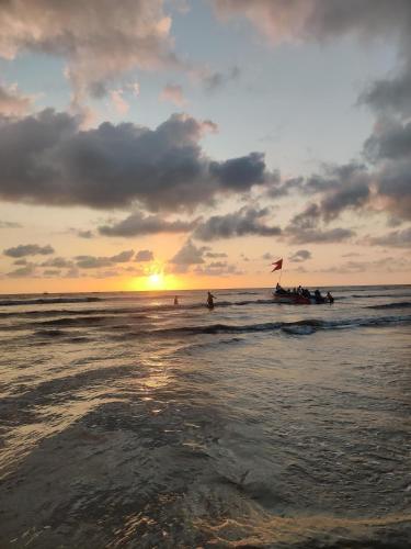 a group of people in a boat in the ocean at sunset at Enliven Homestay Alibag, Alibaug in Nagaon