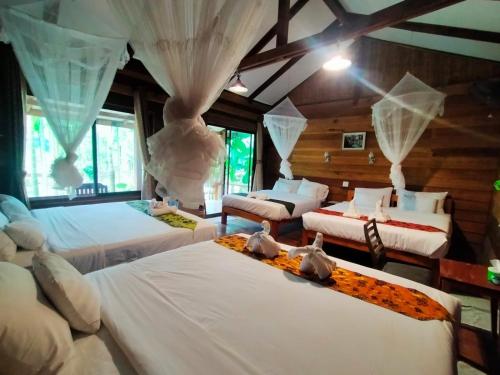 a bedroom with three beds and a room with windows at Phoxay Ngam Resort in Vang Vieng