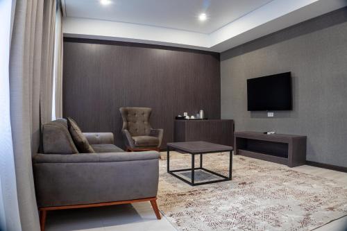 - un salon avec un canapé et une télévision dans l'établissement Resident Hotel Kazybek Bi, à Almaty