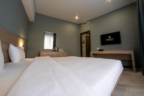 a large white bed in a room with a television at Resident Hotel Kazybek Bi in Almaty