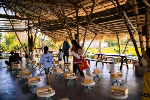 un groupe de personnes debout dans une pièce avec des tables et des chaises dans l'établissement Lang's Pá Mé - Homestay - Bungalow - Camping Krông Pắk, Buôn Mê Thuột, Đắk Lắk, Việt Nam, à Dak Lak