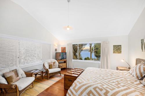 a bedroom with a bed and a couch and a tv at Scotland Island Lodge in Scotland Island