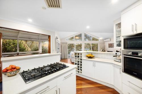 a kitchen with white cabinets and a stove top oven at Scotland Island Lodge in Scotland Island